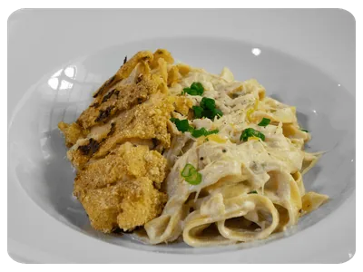 Massa ao molho cremoso acompanhada de frango empanado