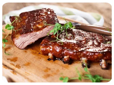 Carne fatiada com molho escuro e ervas sobre uma tábua